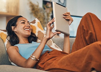 Smiling woman with tablet relaxing on couch