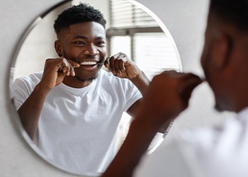 Man smiling while flossing his teeth