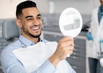 Man smiling at reflection in mirror in treatment chair