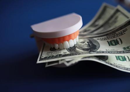 a set of teeth biting onto hundred-dollar bills