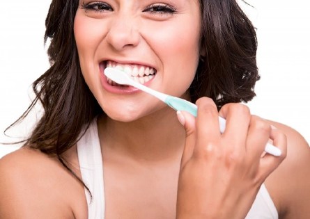attractive woman smiling brushing teeth to care for porcelain veneers