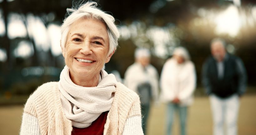 An older woman smiling outdoors.